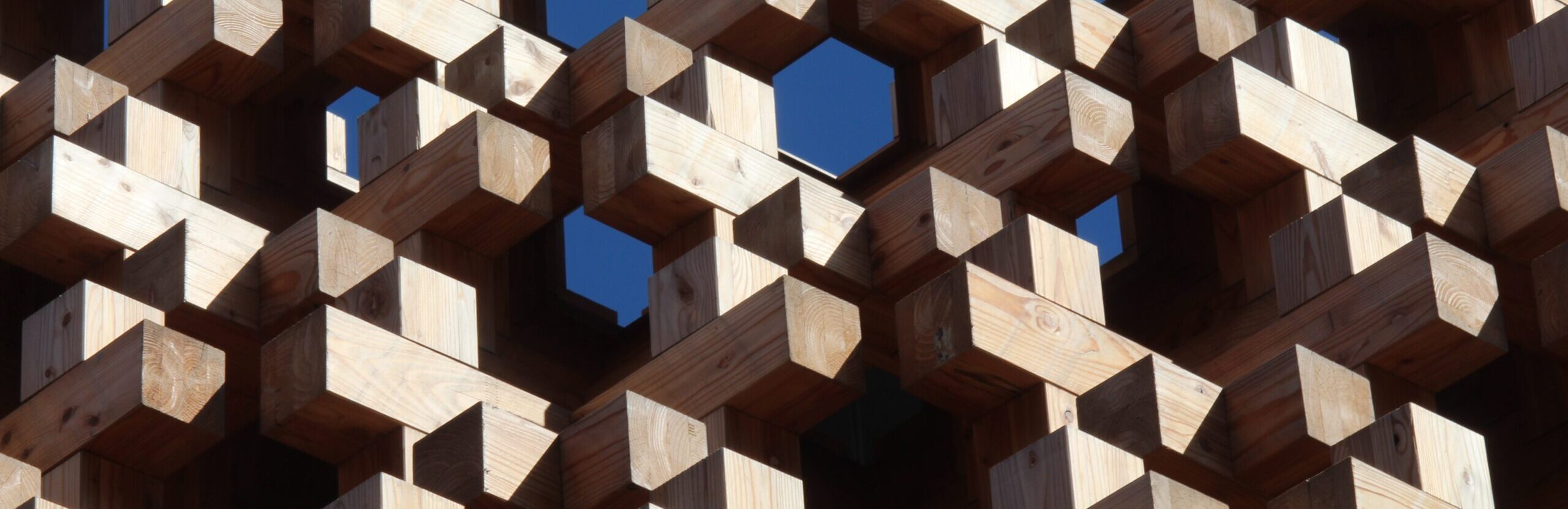 Wooden pieces fit together in an intricate, tessellated outdoor structure. Big projects like these improve the quality of life for the local community.